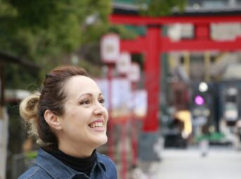 Woman smiling in front of a red shrine gate