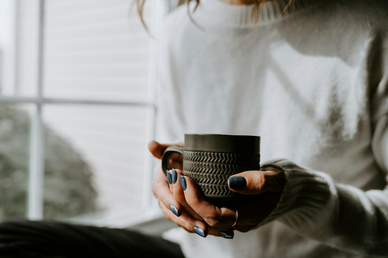 A woman holding a coffee cup in her hands